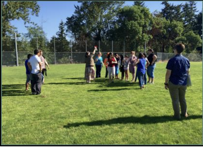 Students and instructors outside doing an activity together on a grass field.