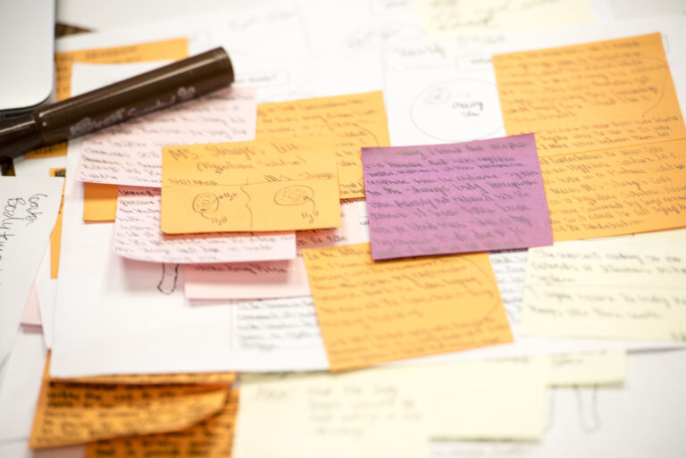 Several annotated post it notes and a pen on a paper.