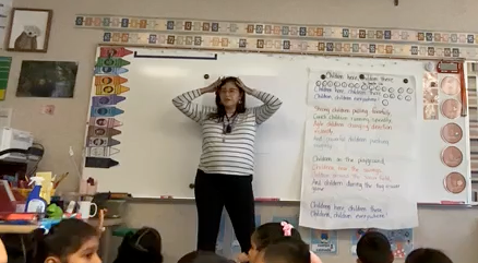 bear lesson teacher standing in front of a classroom with students sitting on a rug